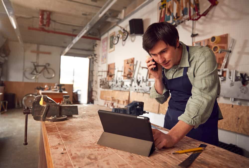 young man talking on the phone at his small business carpentry shop