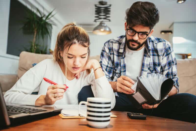 young couple filing 2020 taxes on their living room