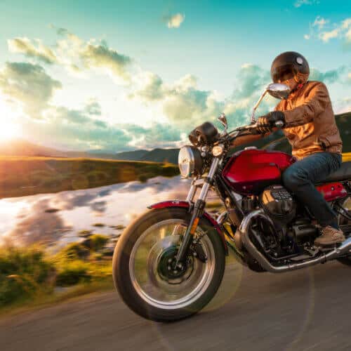 side view of a motorcycle rider on the road during a sunset