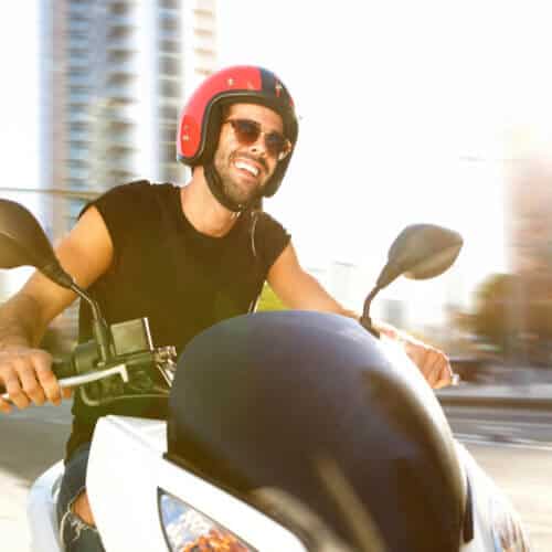 Portrait of handsome man on motorcycle ride in city smiling