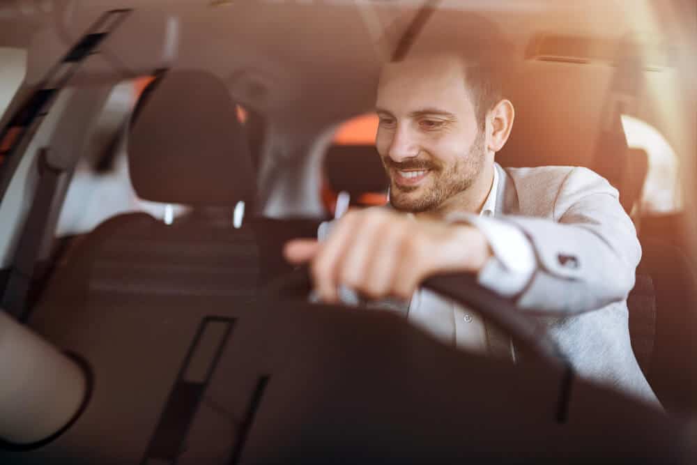 front view man driving car with an insurance policy