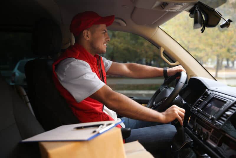 delivery man in commercial auto with boxes and insurance