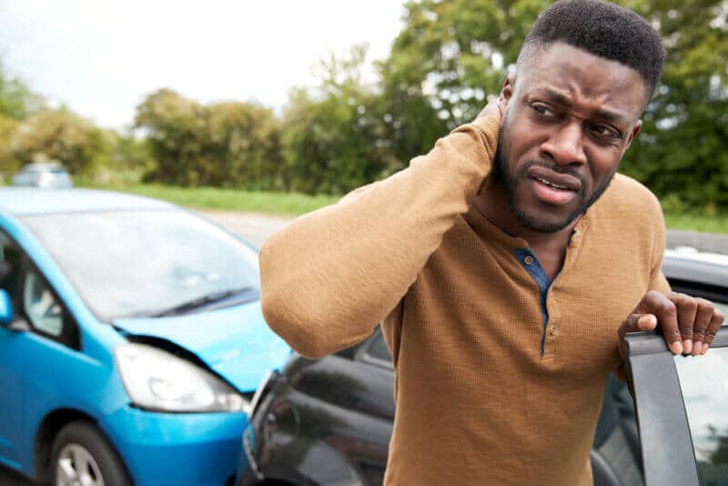 Male Motorist With Whiplash Injury In Car Crash Getting Out Of Vehicle