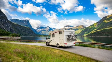 scenic view of a motorhome on a road with a lake in the background