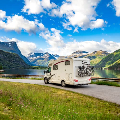 scenic view of a motorhome on a road with a lake in the background