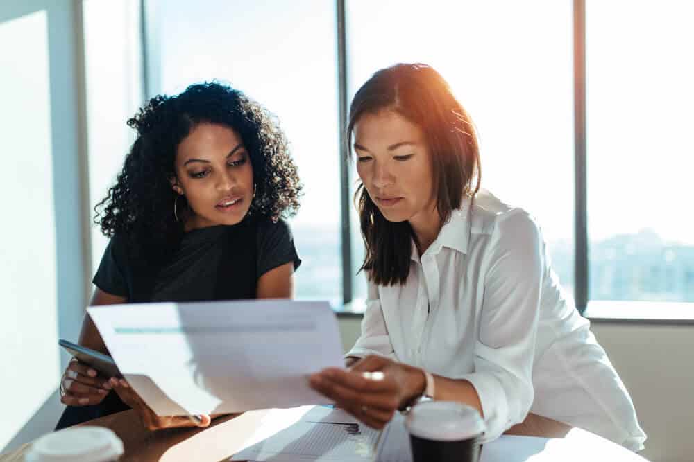 two serious women in office looking at paper document