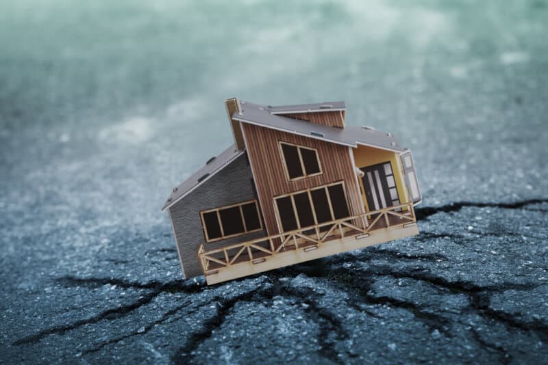 toy house in broken pavement to represent earthquake