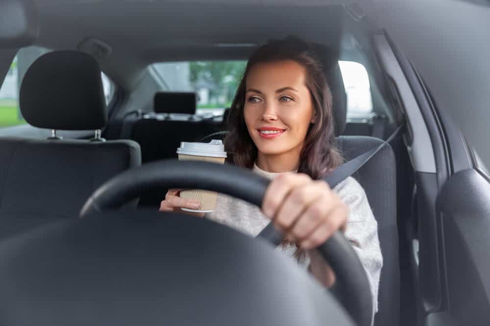 young woman driving car with hands on steering wheel