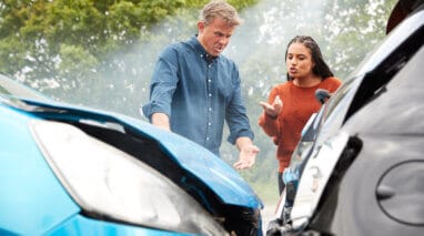 two cars in accident with drivers standing by arguing