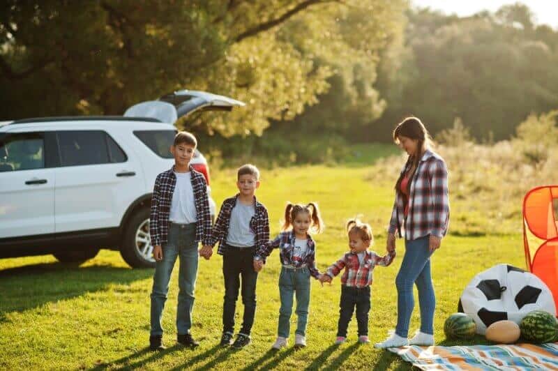 large family standing by car outside