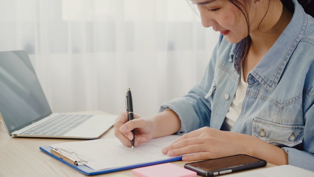 young asian woman making a check list of home inventory