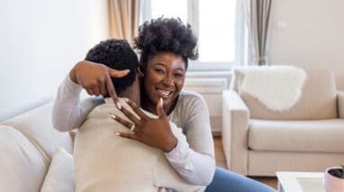 young couple getting engaged, woman smiling with hand up