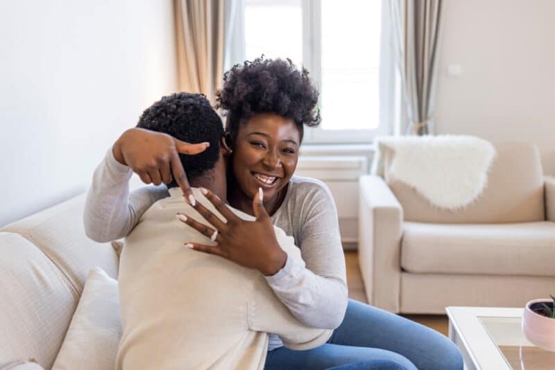 young couple getting engaged, woman smiling with hand up