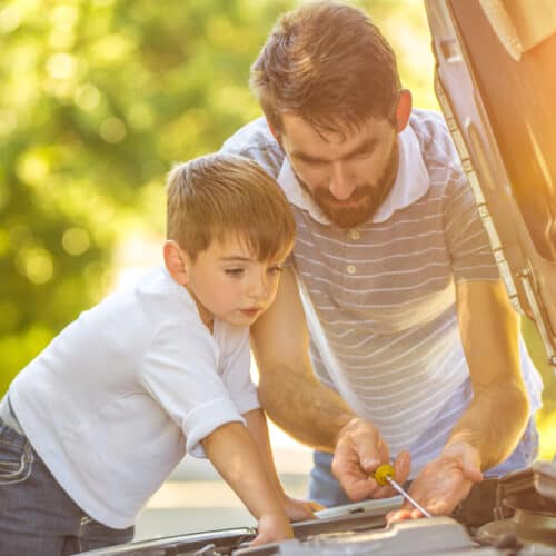 Man and child check the fluids of a car