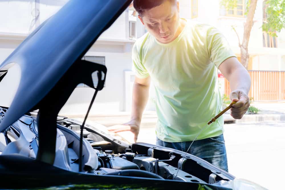 Asian man checks his car's fluid levels