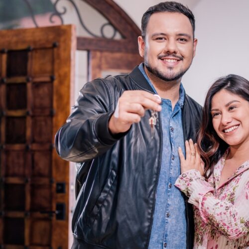 Young Hispanic couple shows off keys to new home