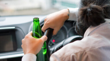 Young man drinks a beer while driving