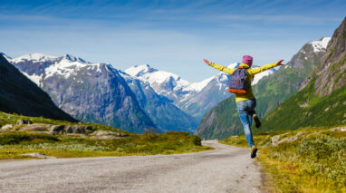 Joyful hiking man jumps in air.