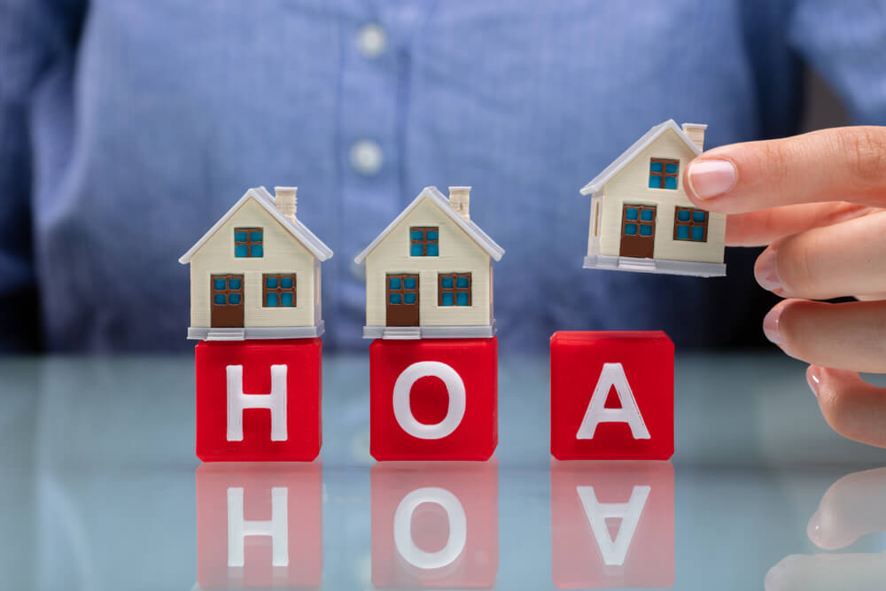 Man's hands place houses on top of the letters spelling HOA.