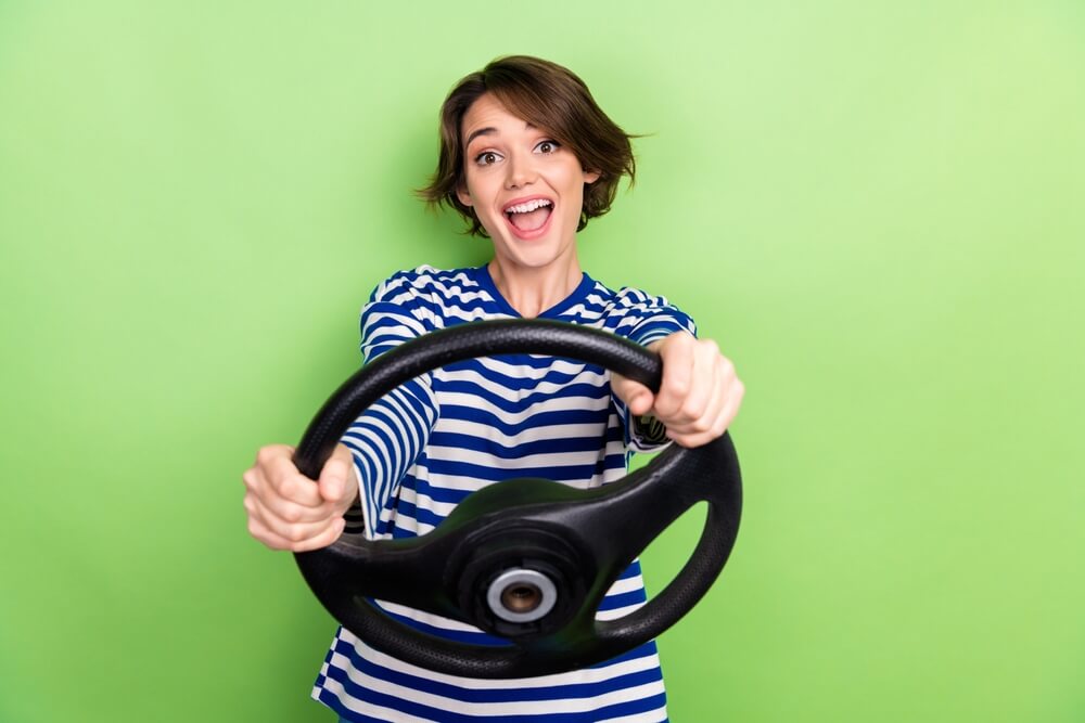 Novice driver holding a steering wheel while smiling