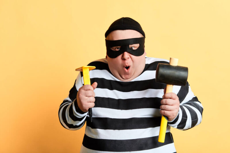 Chubby burglar in striped shirt and mask with sledgehammer and other tools - cheap home insurance in Washington.