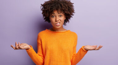 Confused woman in orange shirt with hands in air and puzzled expression on her face - cheap insurance in Washington State.