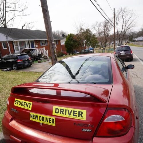 Student driver bumber sticker on a sports car parked on the street - cheapest car insurance in Washington.